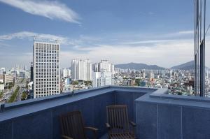 Duas cadeiras numa varanda com vista para a cidade em Eldis Regent Hotel em Daegu