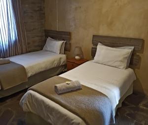 a bedroom with two beds with a towel on the seat at Die Stal in Sutherland