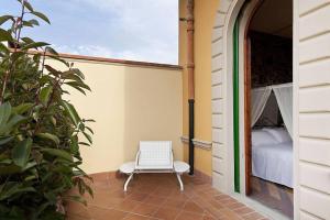 uma cadeira branca sentada num alpendre com uma cama em Cozy Suite By Villa Il Mosaico em Florença