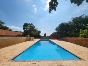 a large blue swimming pool with a brick wall at Guesthouse Serenity in Hartbeespoort