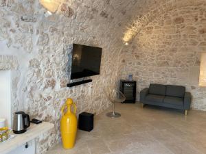 a living room with a couch and a tv on a stone wall at white room Ostuni in Ostuni