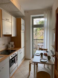 a kitchen with white cabinets and a table and a window at Apartments Dresden Neustadt Apartment KATY in Dresden