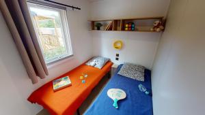 two beds in a small room with a window at Camping Etang de la Bonde in Sannes