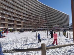 Ludzie bawiący się w śniegu przed budynkiem w obiekcie Studio superdevoluy w mieście Dévoluy