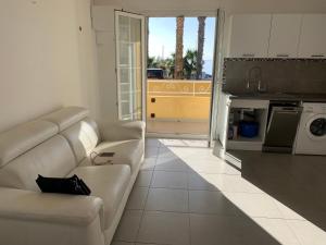 Una sala de estar con un sofá blanco y una cocina. en La Ciotat vue mer emplacement exceptionnel avec parking, en La Ciotat