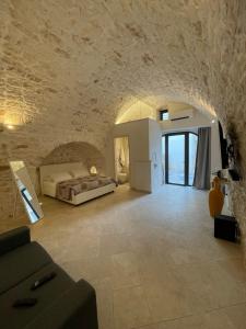 1 dormitorio con cama y pared de piedra en white room Ostuni en Ostuni
