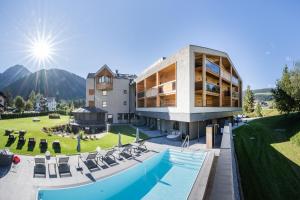 une maison avec une piscine et un bâtiment dans l'établissement Hotel Laurin, à Dobbiaco