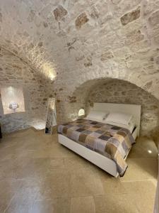 1 dormitorio con 1 cama en una pared de piedra en white room Ostuni en Ostuni