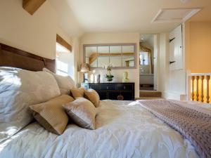 a bedroom with a large bed and a mirror at Thimble Cottage in Lower Slaughter