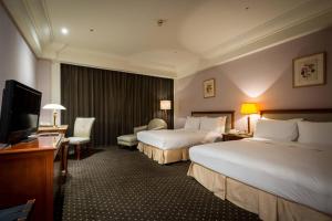 a hotel room with two beds and a flat screen tv at Grand View Hotel in Yuanlin