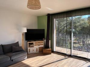 een woonkamer met een bank en een groot raam bij Haut de villa avec jacuzzi et extérieur in Lançon-Provence