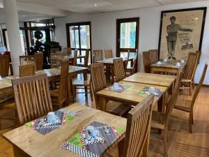 une salle à manger avec des tables et des chaises en bois dans l'établissement Enzo Hôtels - ST Eloy Metz Amneville By Kyriad Direct, à Amnéville