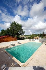 a swimming pool with blue water and two chairs at Camping les 2 salamandres in Arces-sur-Gironde