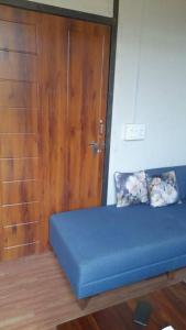 a blue bed in a room with a wooden door at Hedony Farmhouse with 2 Bedrooms and Swimming pool in Rishīkesh