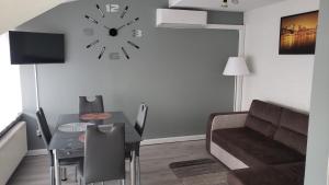 a living room with a table and a clock on the wall at Apartament AGA13 in Mikołajki