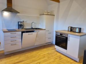 a kitchen with white cabinets and a sink and a stove at Lüttje Deichkieker in Greetsiel