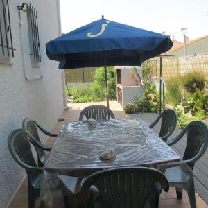 una mesa con una sombrilla azul en el patio en appartement 3 chambres en Bompas