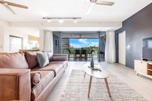 a living room with a brown couch and a table at 'Lady of the Lagoon' Spacious Waterfront Luxury in Darwin