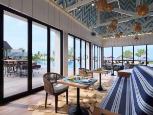 restauracja ze stołami i krzesłami oraz basenem w obiekcie Pullman Lombok Merujani Mandalika Beach Resort w Kuta Lombok