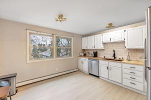 an empty kitchen with white cabinets and a window at Hazelwood Haven near Lambeau! Duplex in Green Bay