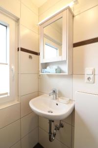 une salle de bain avec un lavabo et un miroir dans l'établissement Langeooger Viermaster - Gelbes Segel, à Langeoog