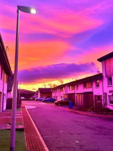 a street with cars parked on a street with a sunset at Woodside retreat holiday home in Aviemore in Aviemore