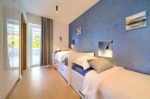 a bedroom with three beds and a blue wall at Vila Tramonto in Pinezici