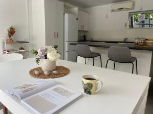 a kitchen with a table with a book and a cup of coffee at family friendly 3BR flat - 3min walk to the beach - self contained in Auckland