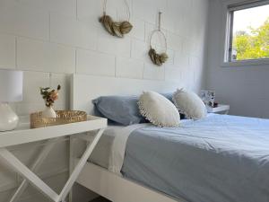 a white bedroom with a bed with pillows on it at family friendly 3BR flat - 3min walk to the beach - self contained in Auckland