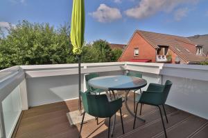 een tafel en stoelen op een balkon met een parasol bij Kiek rin bi Kati - Ferienwohnung 4 in Langeoog