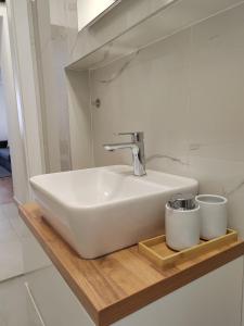 a bathroom sink with two cups on a wooden shelf at S15 Studio Apartment FREE PARKING in Zagreb