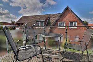 un balcón con sillas, una mesa y una casa en Kiek rin bi Kati - Ferienwohnung 2 en Langeoog