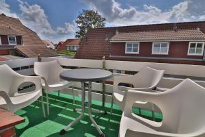 un patio con sillas blancas y una mesa en el balcón en Kiek rin bi Kati - Ferienwohnung 3 en Langeoog