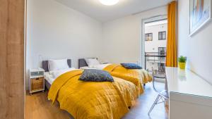 two beds in a white room with yellow blankets at Nexo, Sun & Snow in Puck