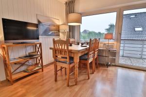 une salle à manger avec une table, des chaises et une télévision dans l'établissement Salini, à Langeoog