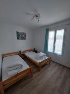 sypialnia z 2 łóżkami i oknem w obiekcie A tribord: maison chaleureuse à 5min de la plage w mieście La Cotinière