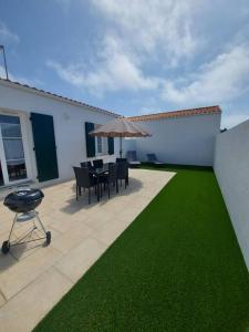 un patio con mesa, sillas y sombrilla en A tribord: maison chaleureuse à 5min de la plage, en La Cotinière