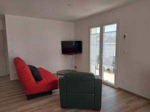 a living room with a red chair and a tv at A tribord: maison chaleureuse à 5min de la plage in La Cotinière