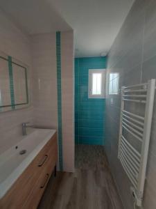 ein Badezimmer mit einem weißen Waschbecken und einer blauen Wand in der Unterkunft A tribord: maison chaleureuse à 5min de la plage in La Cotinière