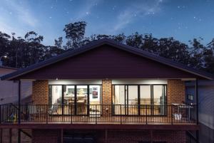 a house with a balcony with tables and chairs at Batemans Bay Delight - Pet Friendly in Batemans Bay
