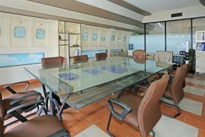 uma sala de conferências com uma mesa de vidro e cadeiras em SUPER OYO 92003 Sky Airlines Guesthouse em Tangerang