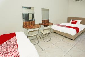um quarto com 2 camas, uma mesa e cadeiras em SUPER OYO 92003 Sky Airlines Guesthouse em Tangerang