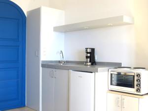 a kitchen with white cabinets and a microwave at MERÁKI VILLA & APARTMENTS in Vamos