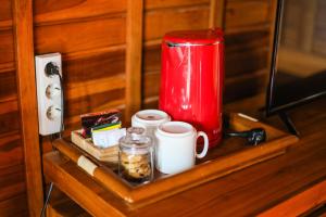 - une étagère avec une cafetière rouge et des tasses dans l'établissement The Polumb Garden Bedugul, à Tabanan
