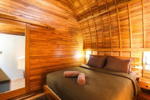 1 dormitorio con 1 cama en una habitación de madera en The Polumb Garden Bedugul, en Tabanan