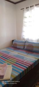 a bed with a colorful striped sheets and a window at Dhadas place in San Vicente