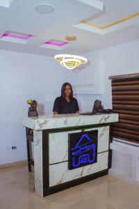 a woman standing behind a counter with a sign on it at Go2Hotel45 in Lagos