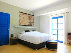 a bedroom with a white bed and a blue door at MERÁKI VILLA & APARTMENTS in Vamos