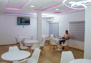 a man sitting at a table in a room with tables and chairs at Go2Hotel45 in Lagos