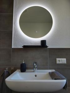 a bathroom sink with a round mirror on the wall at Unterm Walmdach No. 3 in Dinkelsbühl